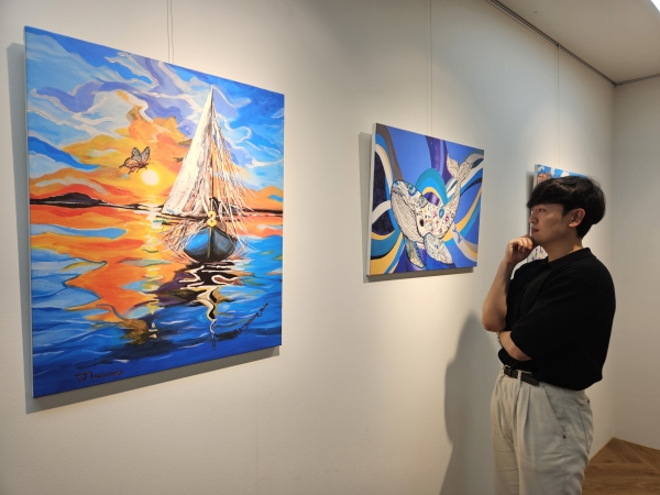 현대제철 직원이 ㈜올모용인 사업장에 걸린 소속 발달장애인 작가들의 작품을 감상하고 있다. /현대제철